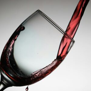 Dramatic capture of red wine being poured into a tilted glass, showcasing elegance and flow.