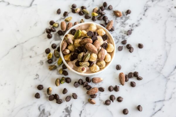 A bowl of mixed nuts and chocolate chips on a marble surface, perfect for healthy snacking.